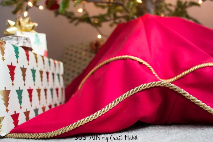 Close up view of gold piping on the edge of a tree skirt made with red velour