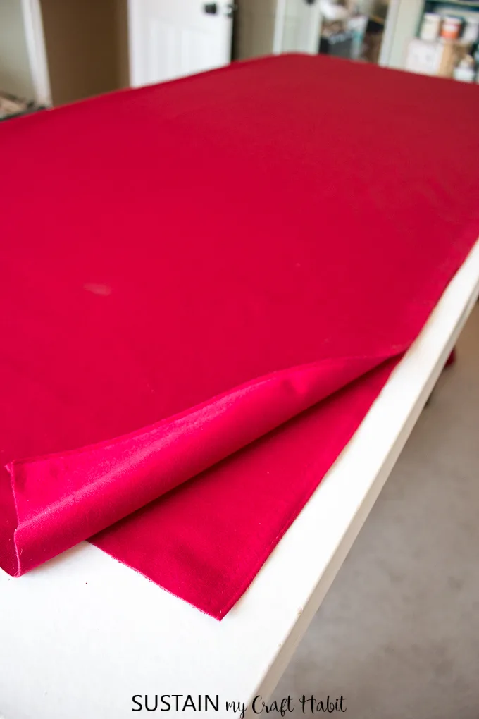 A large piece of red velour on a table being prepared to make a tree skirt for Christmas