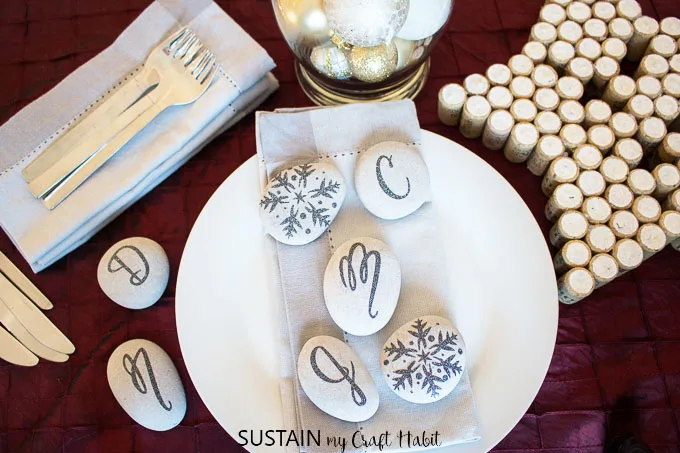 A festive table setting displaying monogrammed and embellished stones using a design from the Cricut Design Space.