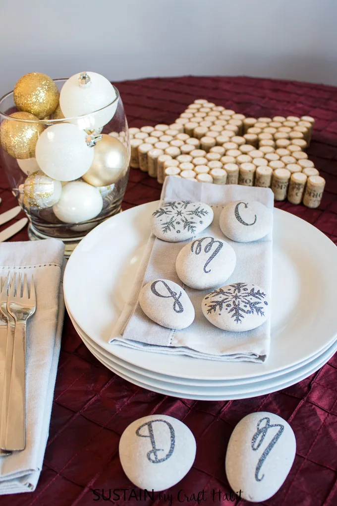 A festive place setting embellished with snowflake and monogram stones as napkin settings. An example of a simple rock crafts ideas using the Cricut Maker.