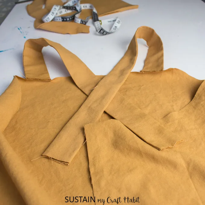 Arranging the shoulder straps to criss-cross at the back of the utility apron pattern