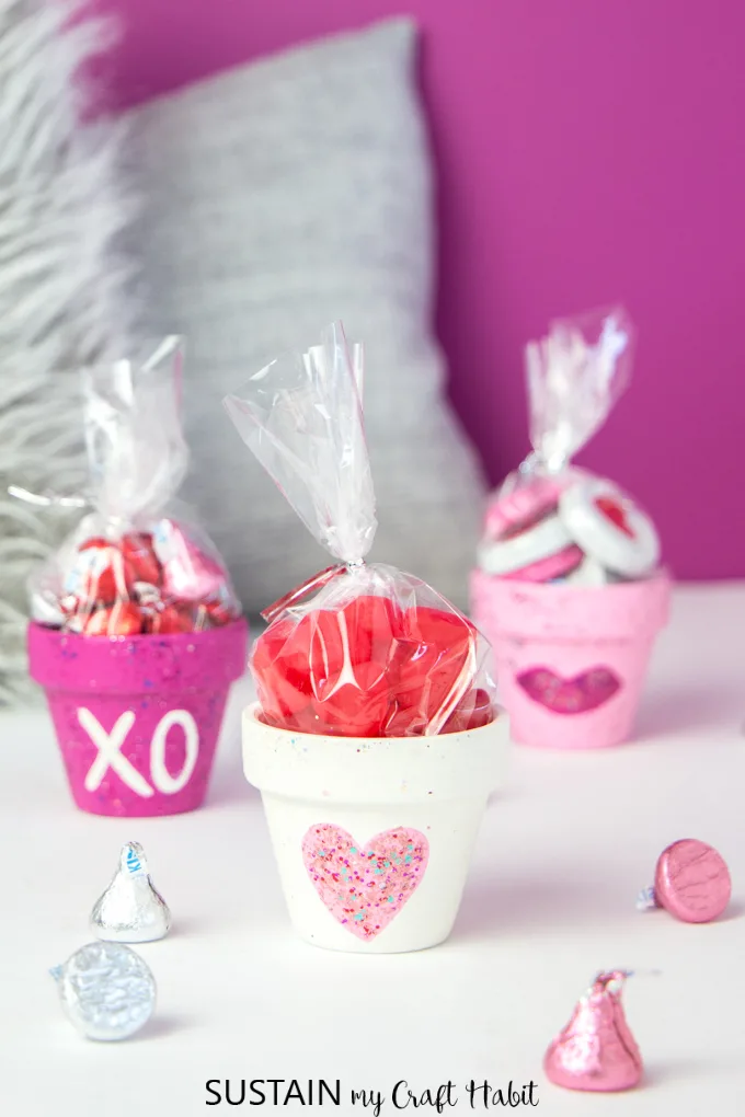 Mini clay pots painted in pinks and whites, filled with sweet treat for Valentine's Day
