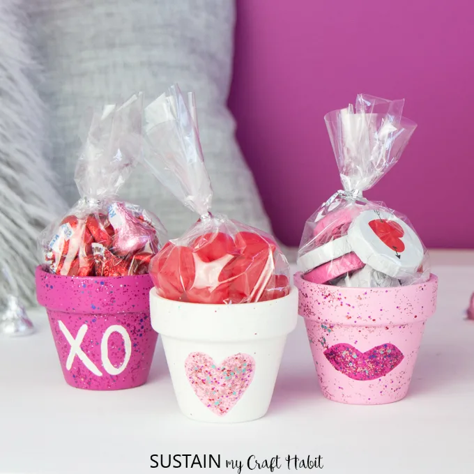 Pink and white painted clay pots filled with sweet treats for Valentine's Day