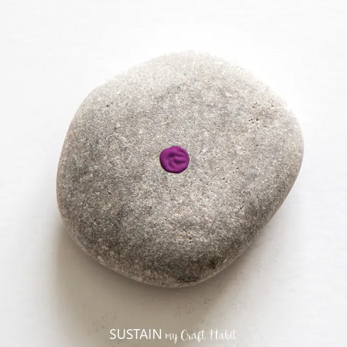 Purple dot painted on the center of a beach stone