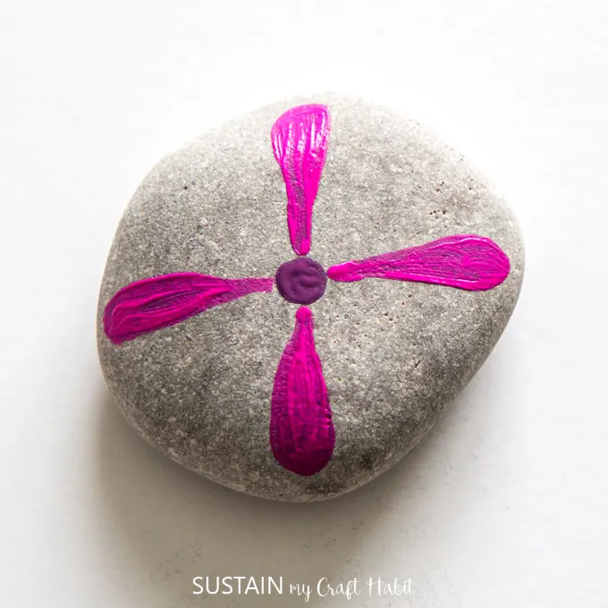 Four pink petals extending from the center point on the rock