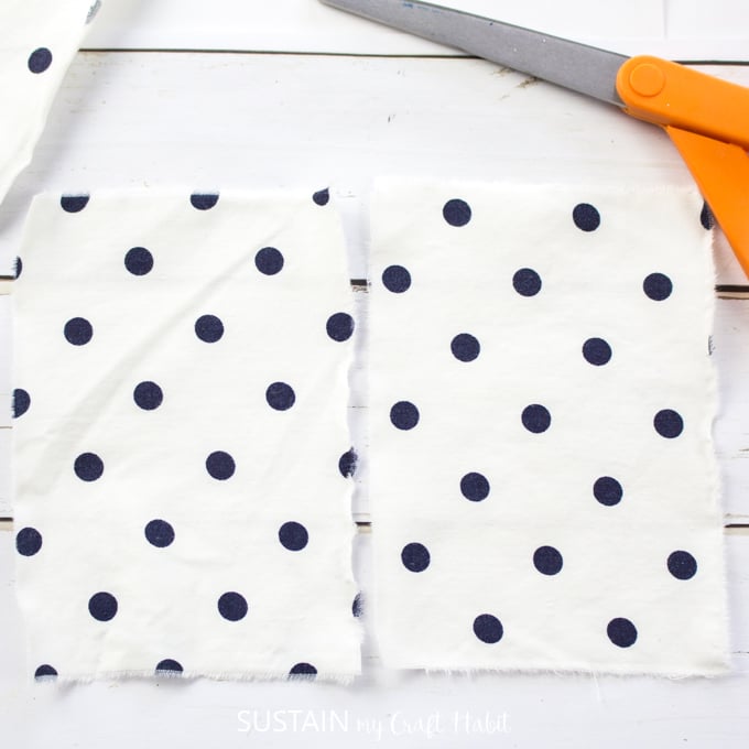 Two pieces of white fabric with large black polk-a-dots cut to size for the craft.