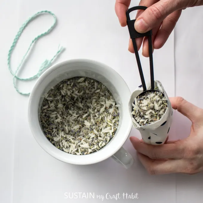 Placing a spoonfull of lavender and rice mixture into the cloth bag.