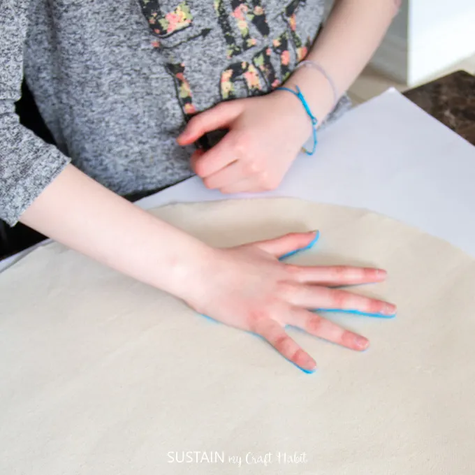 Child pressing their painted hand down onto canvas fabric