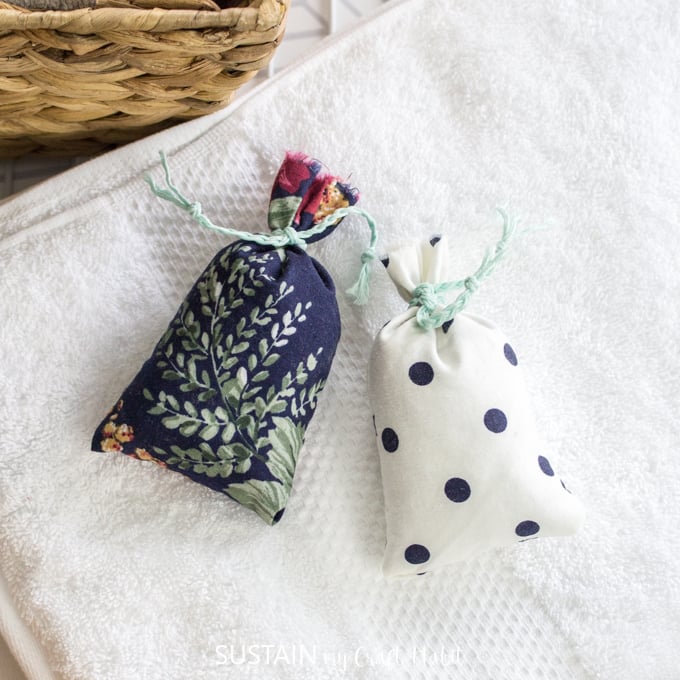 Overhead view of two finished smell bags. The sachets are tied off with pieces of braided teal embroidery floss.