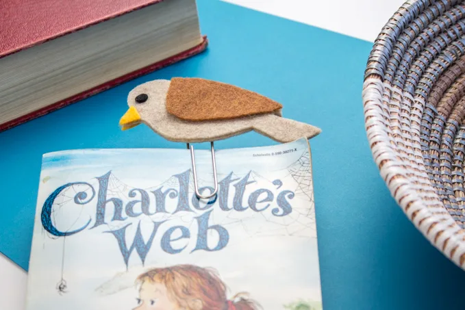 A completed brown felt bird bookmark placed in the cover of the book Charlotte's Web.