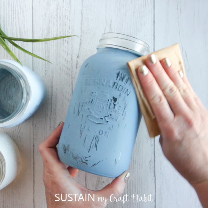 Distressing the blue painted mason jars with sandpaper.