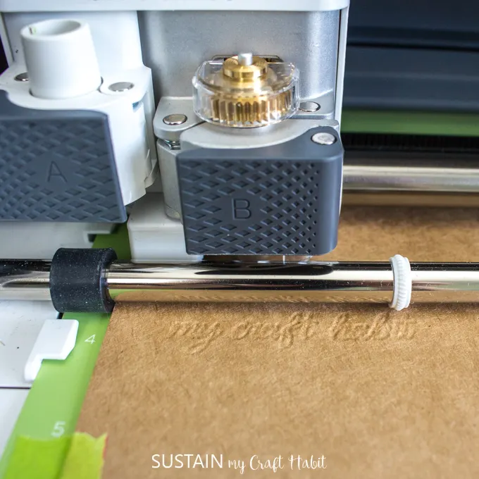 Close up image of the Cricut Maker in action, debossing a piece of light chip board.