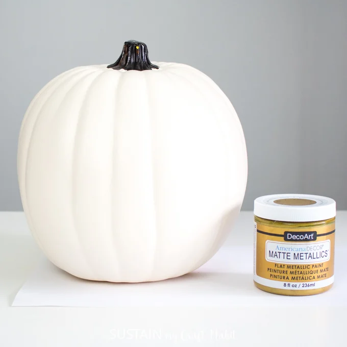 One white pumpkin and one jar of DecoArt matte metallics paint in gold color.