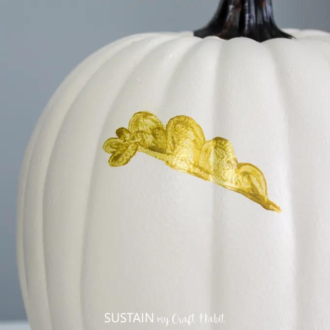close up of white pumpkin and half painted gold leaf.