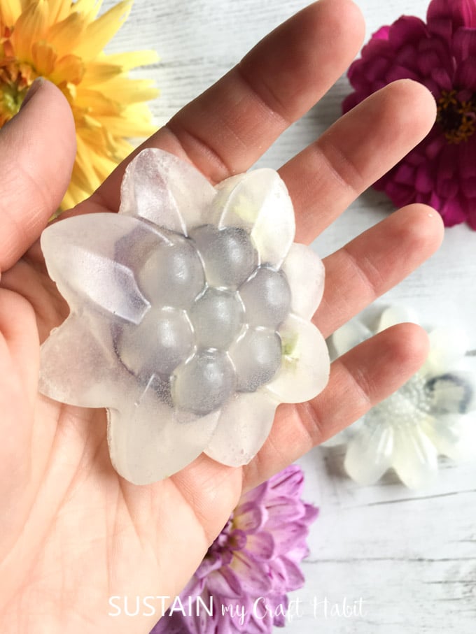 Hand holding a completed botanical soap in the shape of a flower.