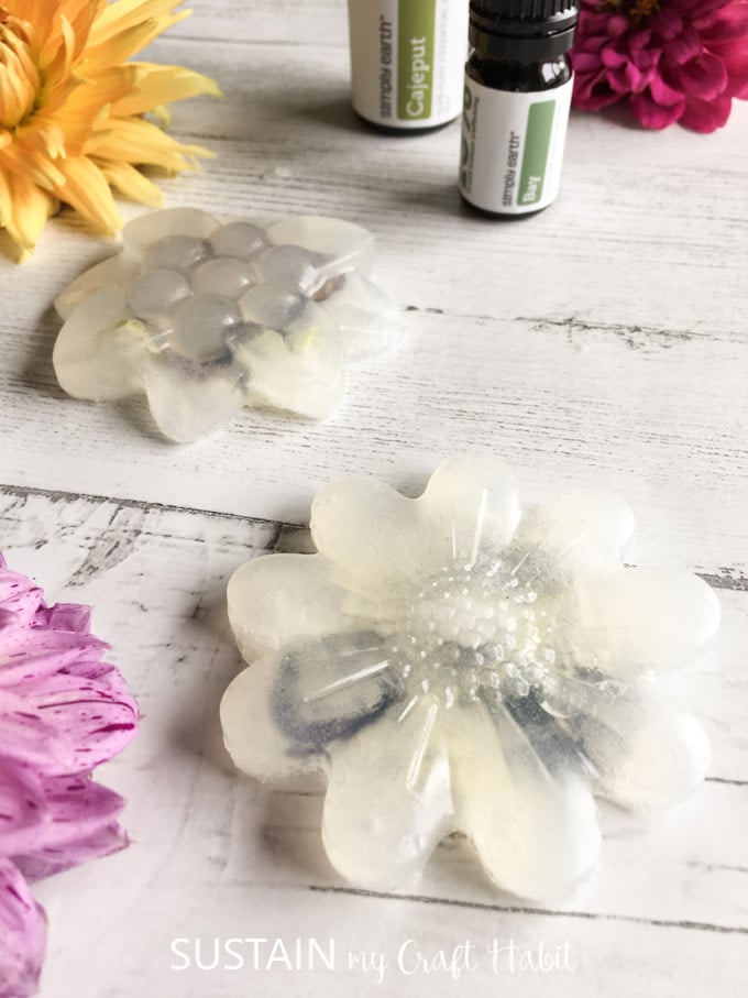 Close up image of the completed botanical glycerin soaps with bay and cajeput essential oil bottles in the background.