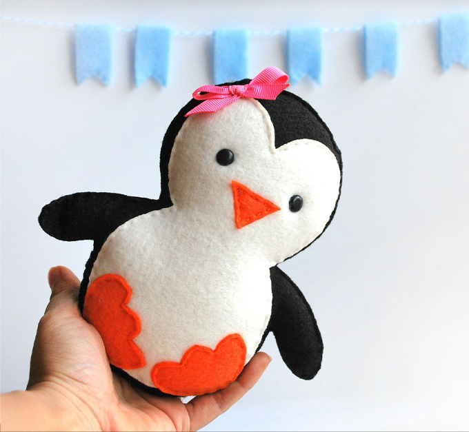 Holding a felt penguin with a pink bow.