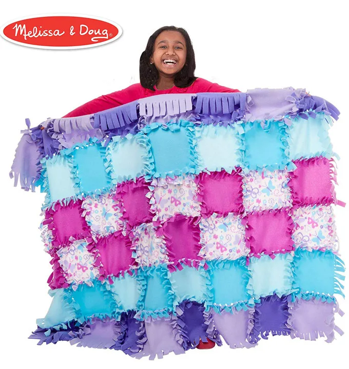 Girl showing a completed fleece quilt.