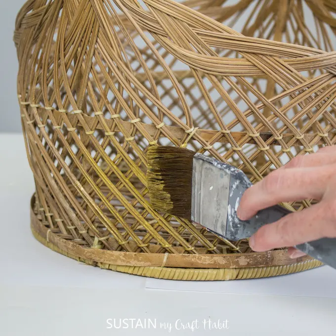 Close up of hand painting wicker basket with gold paint.