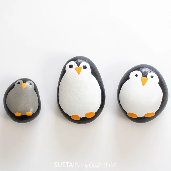 Three completed penguin rocks on a white surface.