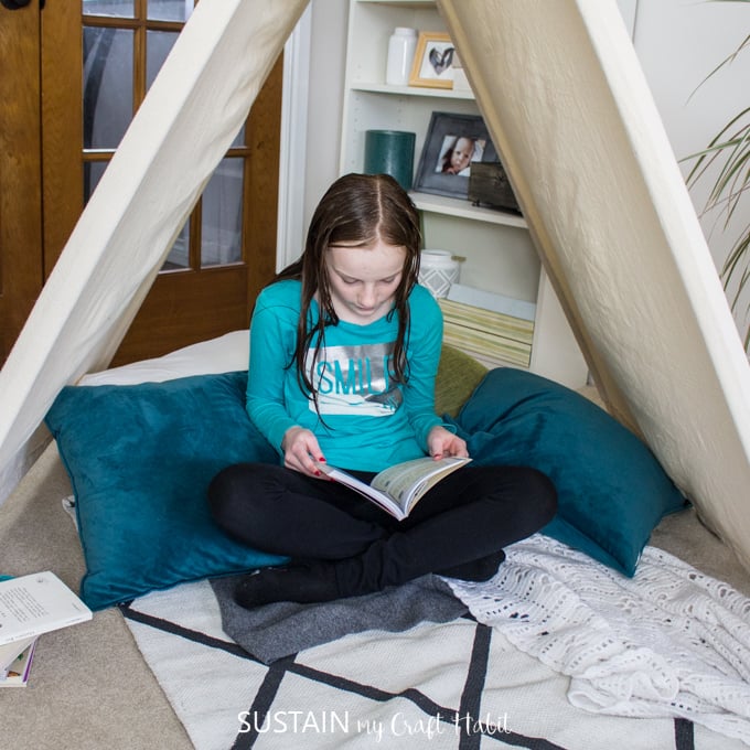 Child reading a book in a DIY kids indoor tent.