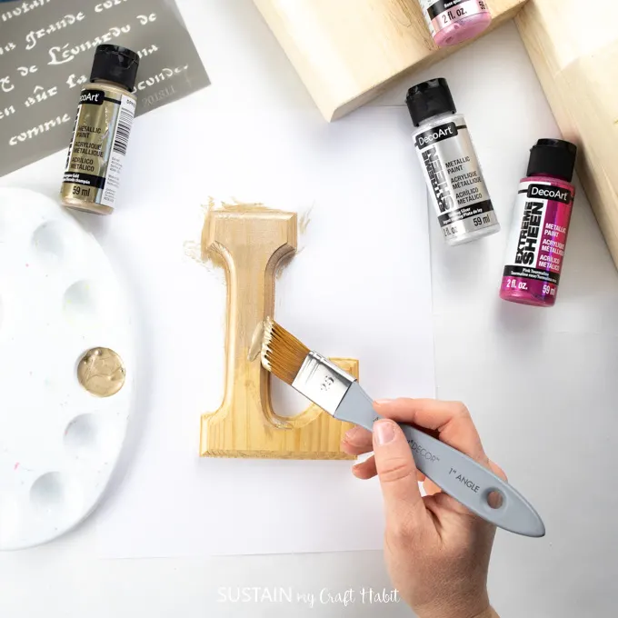 painting the letter L with gold paint.