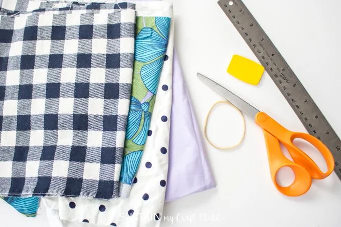Supplies needed to make a scrunchie with a hair tie including fabric, hair elastic and sewing scissors.