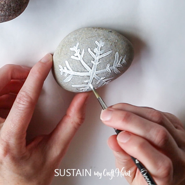 painting lines for a snowflake on a grey rock.