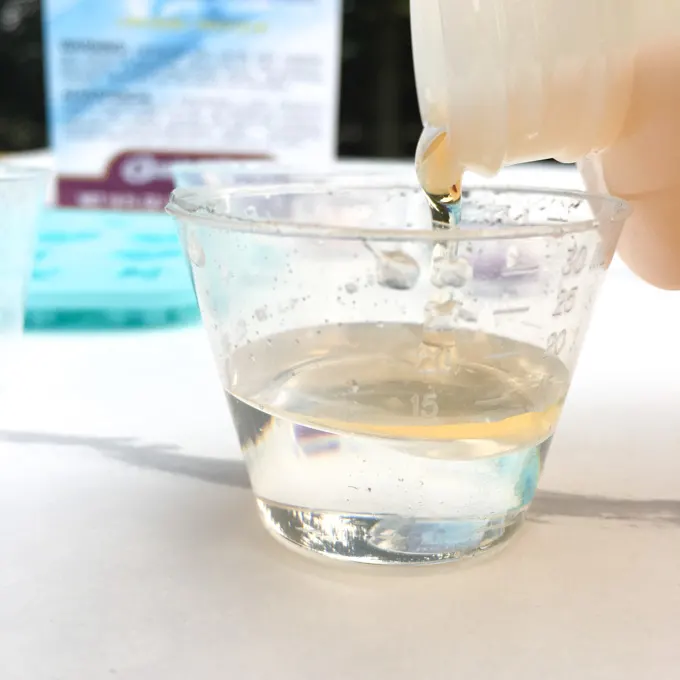Pouring resin and hardener in a clear plastic cup.