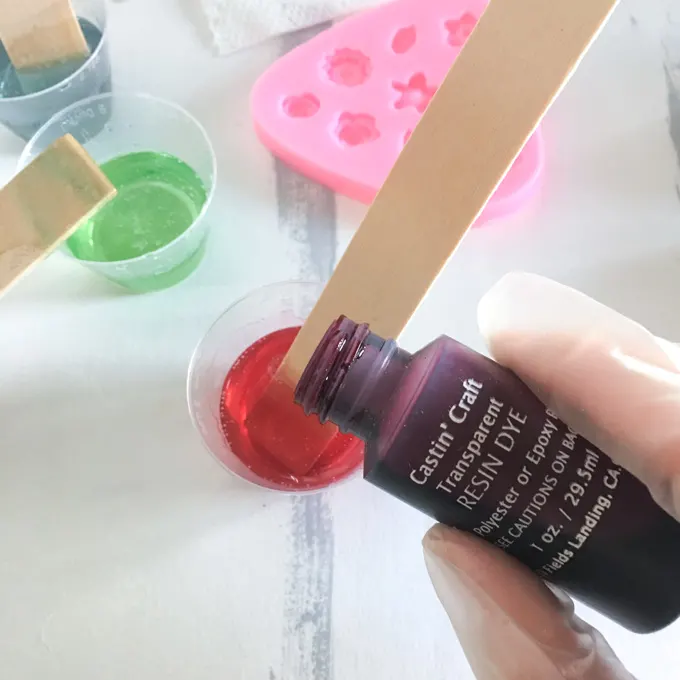 Adding color to the resin mix and using a popsicle stick to stir.