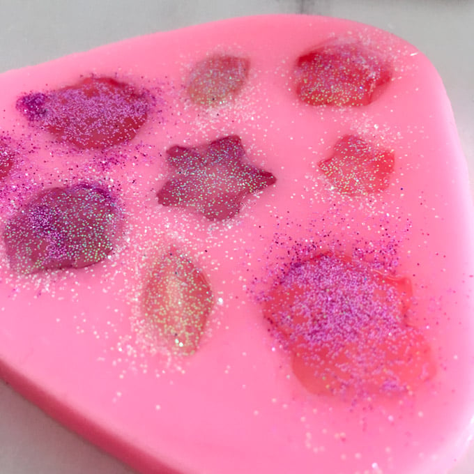Sprinkling glitter over the poured resin in the pink silicone mold.