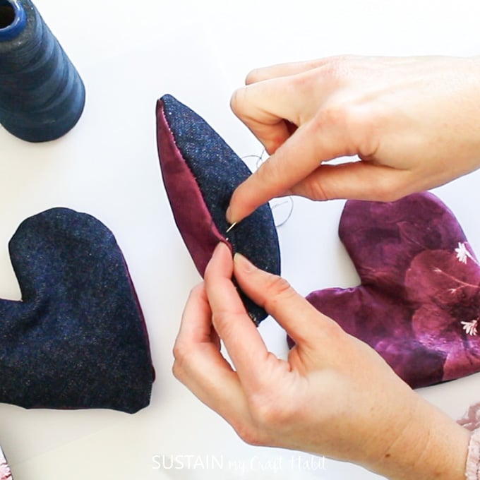 Sewing the fabric hearts with a needle and thread.