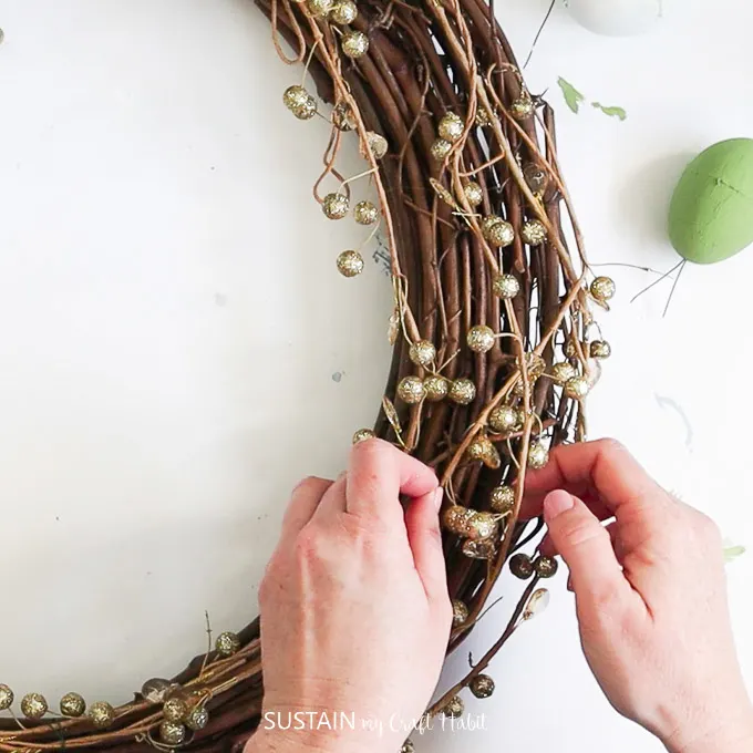 Attaching gold garland to the grapevine wreath.