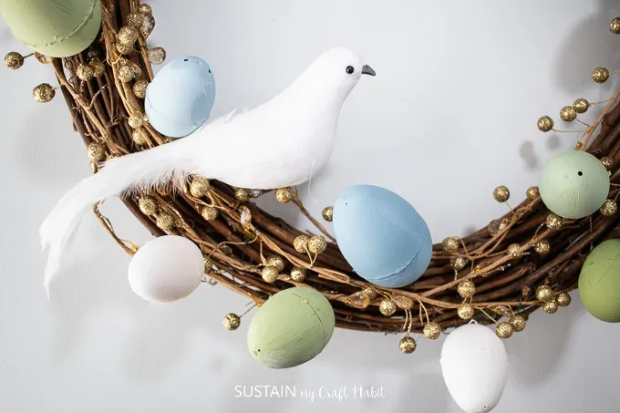 Close up of decorative bird and painted Easter eggs on the grapevine wreath.