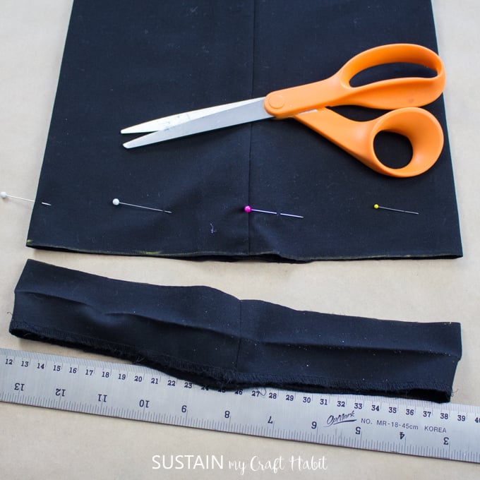 Cutting off excess length of fabric to shorten a wide leg pant.
