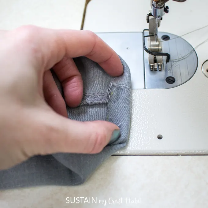 Close up image of holding the new hem in place for a stitched pant hem.