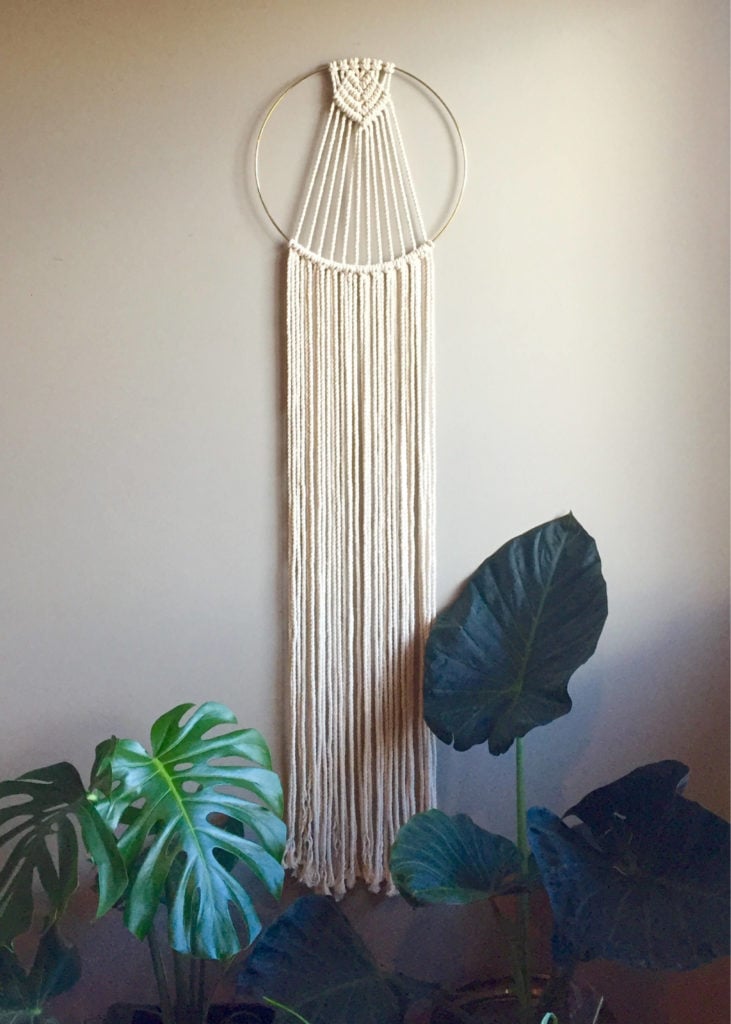 Completed project of cream colored rope knotted around a gold hoop ring made from a macrame wall hanging kit.