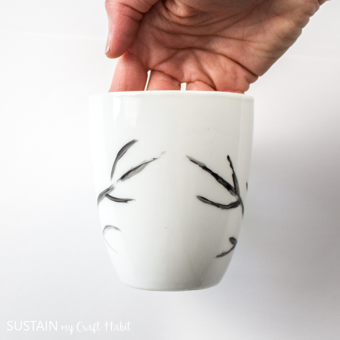 Holding the white mug to show the black painted diagonal lines facing each other.