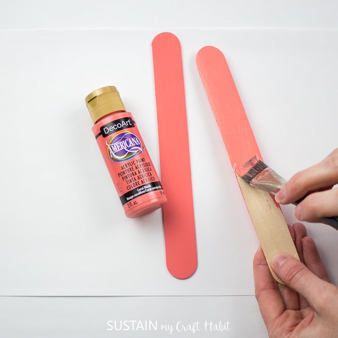 Painting a wooden popsicle stick in DecoArt coral pink color.