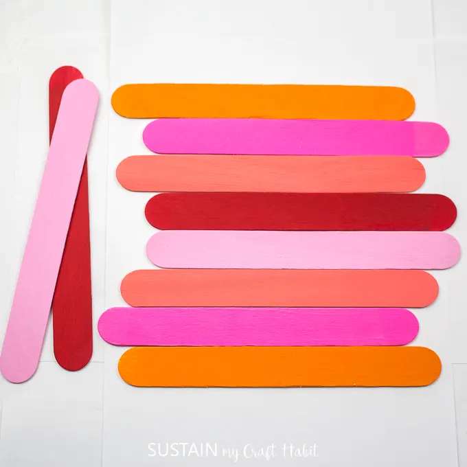 Painted popsicle sticks faced down and assembled horizontally with 2 sticks off to the side.