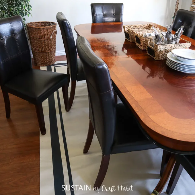 DIY painted canvas rug beneath a large wooden dining table