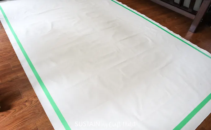 placing painter's tape on the canvas to prep for painting stripe pattern
