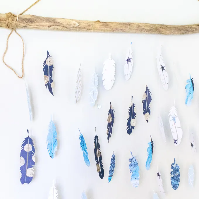 Finished wall decor paper feathers hanging from a long piece of driftwood.