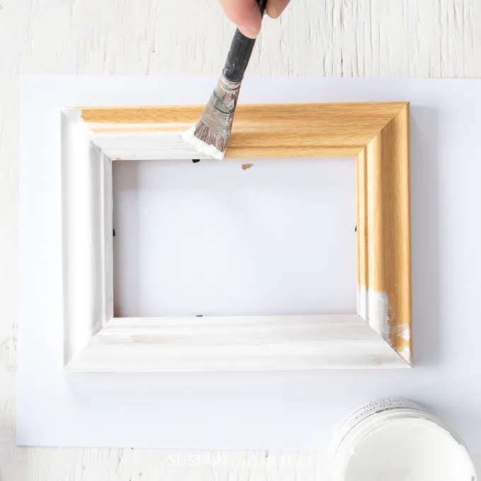 Painting a wood picture frame with white paint.