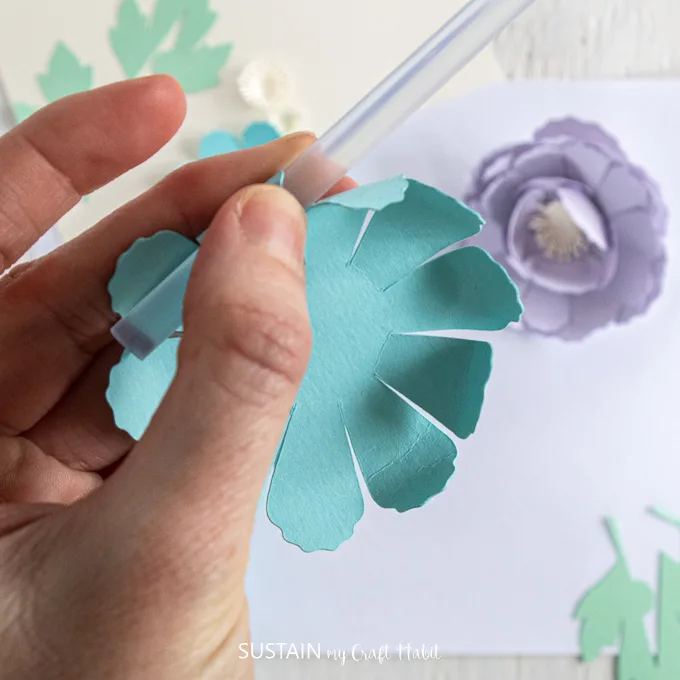 Using a straw to curl the ends of the cut out blue flower.