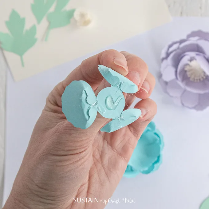 Adding glue to the back of the small blue flower petal.