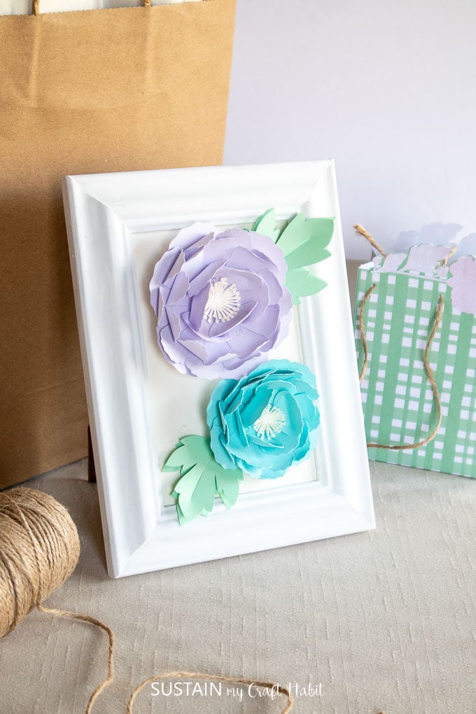 Blue and purple 3D peony flowers placed in a white picture frame. 