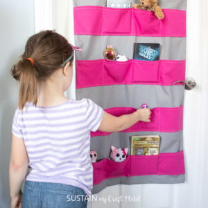 girl using the hanging toy storage to sort her toys