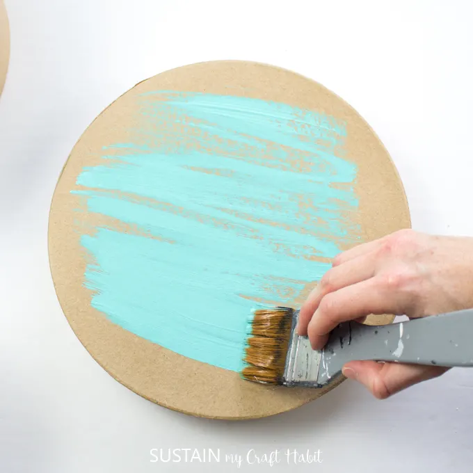 Painting the craft hat box lid with blue paint.