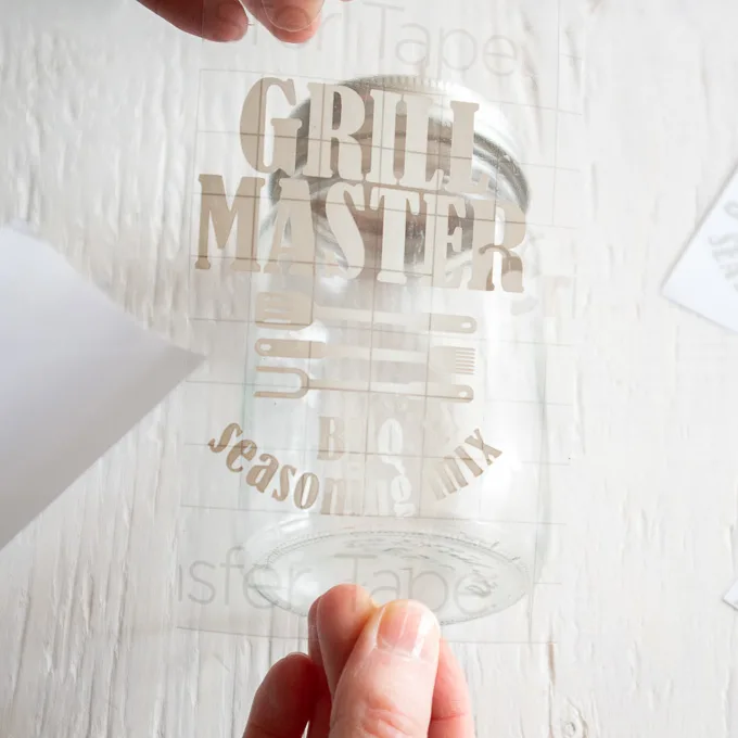 Positioning transfer tape on the front of a glass mason jar.